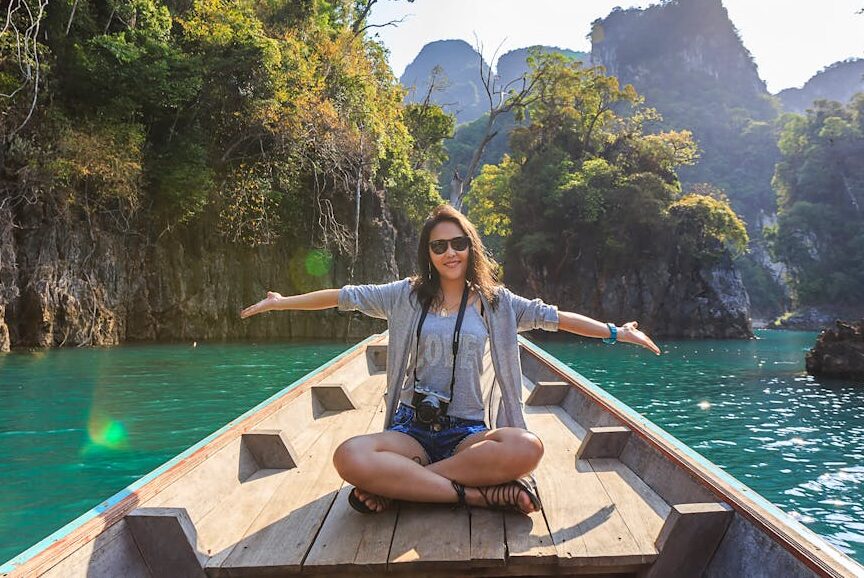 Mujer de viaje en un barquito. ¿Es legal irse de vacaciones cobrando el paro o la baja?