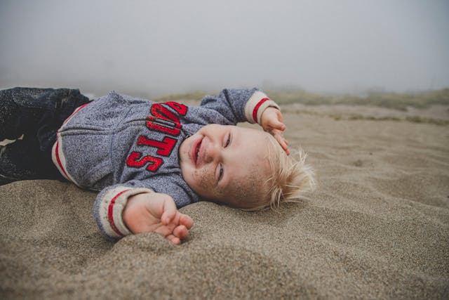 Hijo de família numerosa sonriendo en la arena de la playa