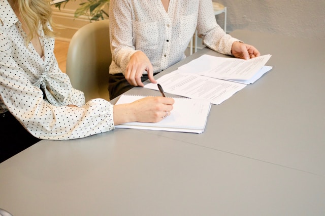 Una mujer con una ayudante dandole información sobre multas en la declaración de la renta.